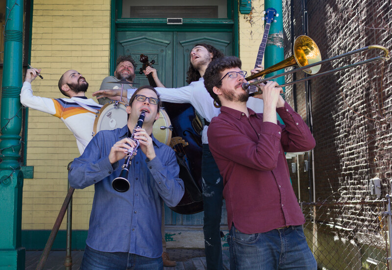 Five musicians goof around on a yellow and green front porch