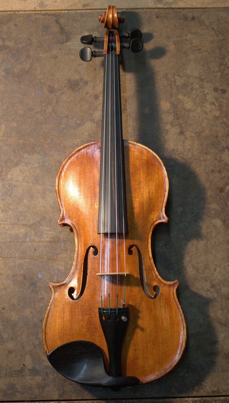 Front view of a Guarneri pattern vioiln featuring antiqued orange varnish