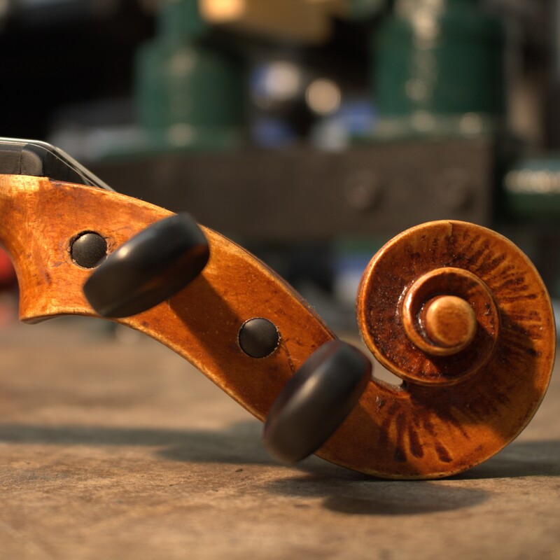 Image shows a violin scroll with heavy tool marks along the inner faces of the volute